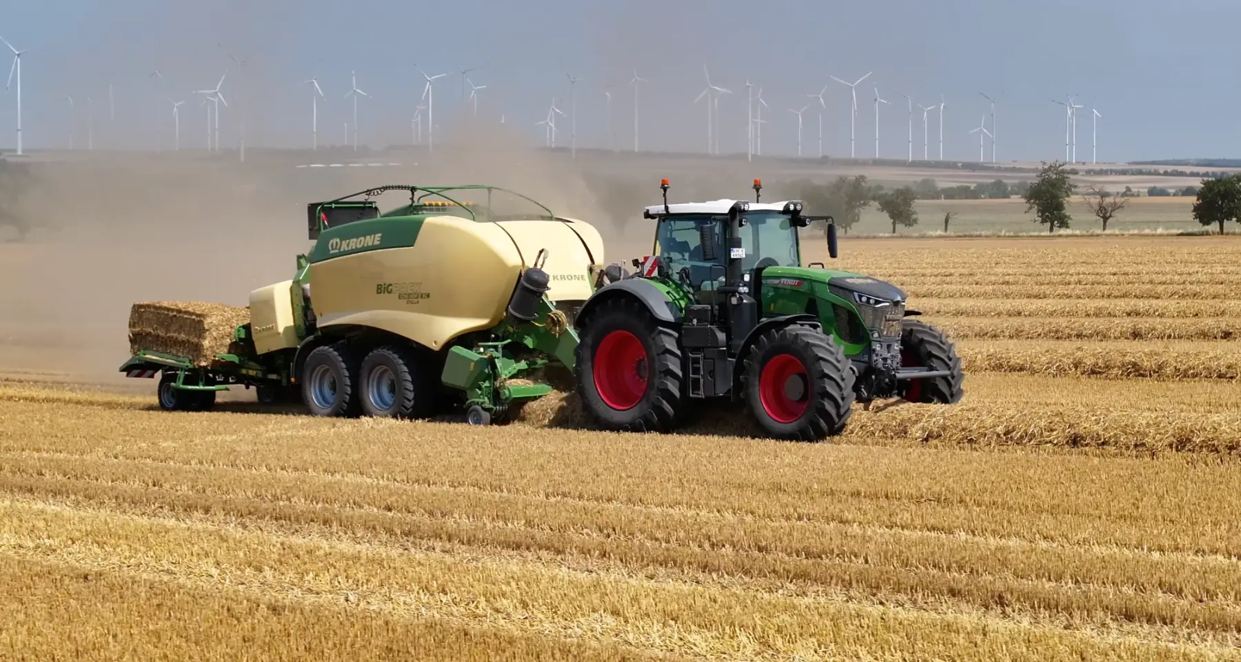 Traktor mit Großballenpresse bei der Strohernte